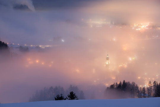 Dobbiaco village in the fog at twilight, Pusteria valley, dolomites, Trentino Alto Adige, Italy, Europe
