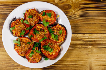 Baked eggplants with tomatoes and cheese on wooden table. Top view
