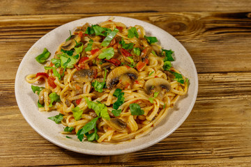Pasta with mushrooms and tomato sauce on wooden table