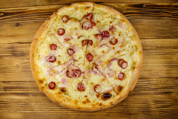 Delicious fresh pizza with sausage, red onion and cheese on a wooden table. Top view