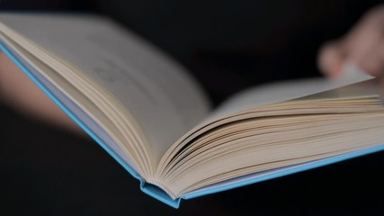 Hand and book: reading a book and holding your fingers along the lines. A woman's hand holds a book and moves her fingers along the page while reading. The reader of the book holds - Powered by Adobe