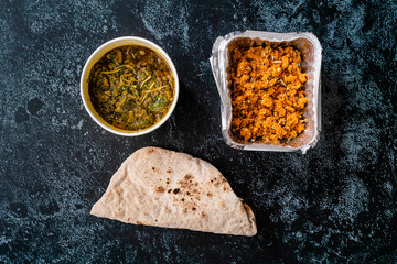 Take Away Indian Dish Spinach Lamb Palak with Gajar ka Halwa / Helva is a carrot-based sweet dessert pudding from India and Flat Bread Chappati in Plastic Container Box / Package.