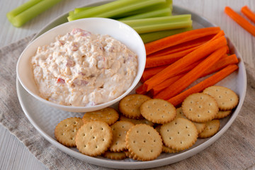 Homemade Pimento Cheese Dip with carrots, celery and crackers, side view. Close-up.