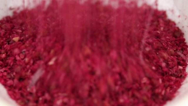 Ground Sumach berries fall in a glass transparent bowl, close-up