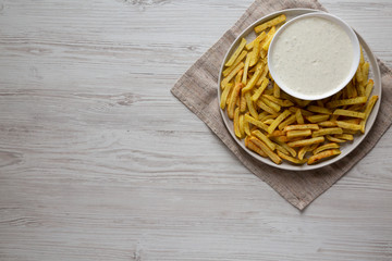 Homemade Crispy Ranch Fries on a gray plate on a white wooden surface, top view. Overhead, from above. Copy space.