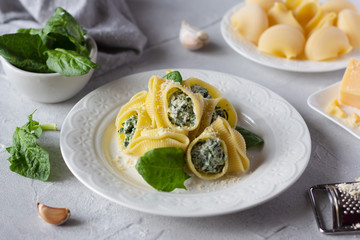 Italian pasta lumaconi stuffed with spinach and ricotta cheese, sprinkled with grated parmesan