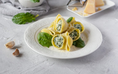 Italian pasta lumaconi stuffed with spinach and ricotta cheese, sprinkled with grated parmesan. Horizontal orientation