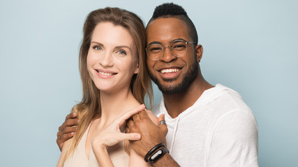 Portrait of happy diverse couple hug making picture in studio