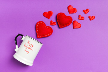 Top view of red textile hearts splashing out of a cup on colorful background. Happy Valentine's day concept