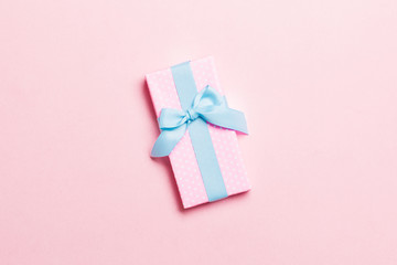 Top view Christmas present box with blue bow on pink background with copy space