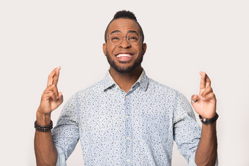 Hopeful black man cross fingers hope for luck