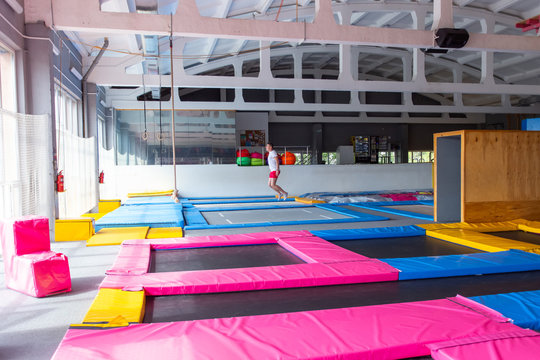 Fitness, fun, leisure and sport activity concept - Handsome happy man jumping on a trampoline indoors