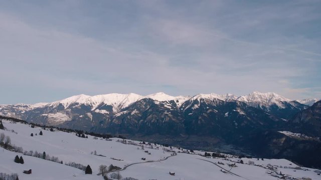 Aerial drone descending shot over a winter landscape with snowy capped mountains.