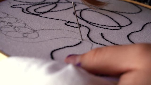 Mano femenina bordando textura abstracta sobre tela blanca
