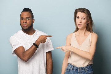 Frustrated diverse man and woman point finger blaming each other