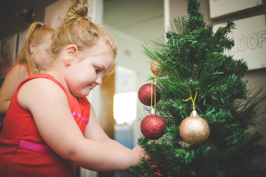 Close up image of two young girls / sisters, decorating a Christmas tree for the holidays