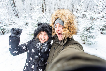 Season, love, technology and leisure concept - happy couple taking selfie by smartphone over winter background