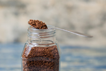 Spoon with instant coffee over the can closeup. Coffee granules macro.