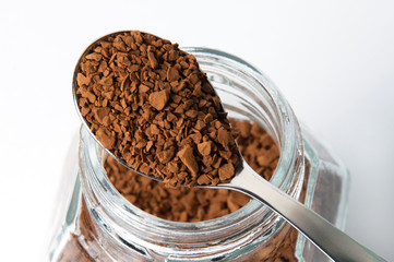 Instant coffee granules in a spoon, macro, on white background