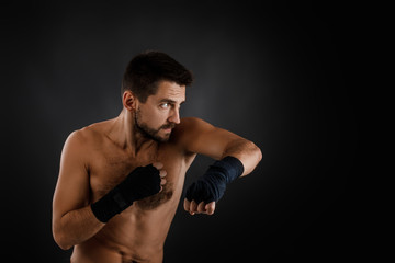boxer man with bandage on hands training before fight and showing the different movements on black background