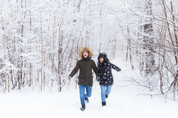 Fototapeta na wymiar Happy couple walking through a snowy forest in winter