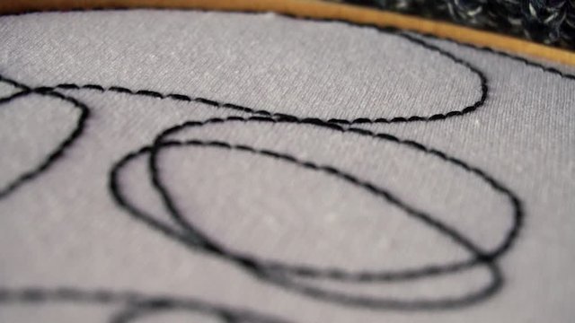 Mano femenina bordando textura abstracta sobre tela blanca