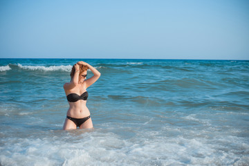Fototapeta premium Plus size nice young woman with full hips and pretty figure in fashionable swimsuit rest at sea, vacation and trip concept