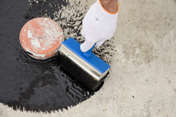 Worker applies bitumen mastic on the foundation