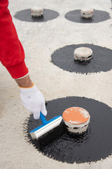 Worker applies bitumen mastic on the foundation