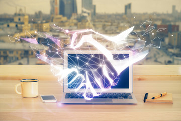 Desktop computer background in office and handshake hologram drawing. Double exposure. Pertnership concept.