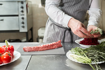 Ribs lamb ready for marinade with rosemary. Cooking with fire in frying pan. Professional chef in a kitchen of restaurant cooking.