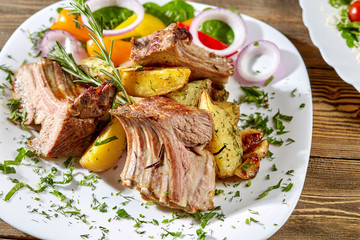 Grilled rack of lamb with fried potatoes and fresh vegetables. Dinner at restaurant.