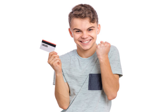 Portrait of happy teen boy with credit card, isolated white background. Smiling child celebrating his success. Teenager showing credit or debit card having fun.