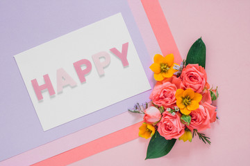 Flat lay colorful flowers composition on bright paper background, blank with text Happy, copy space