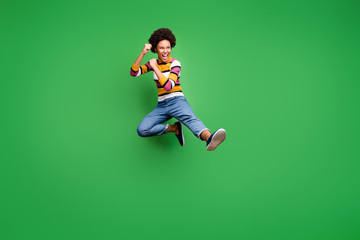 Full length photo of crazy afro american girl hipster jump train kickboxing fight copyspace fall sport kick legs fists wear trendy denim jeans isolated over green color background - obrazy, fototapety, plakaty