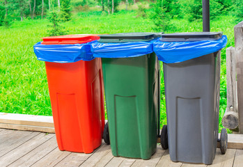 Three garbage cans with blue plastic bags