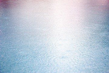 Blue water. Rain. Drops. Surface texture. Pool. Summer. Rainy day.