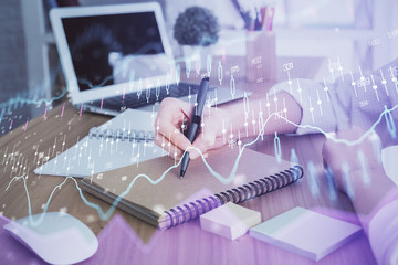 Financial charts displayed on woman's hand taking notes background. Concept of research. Double exposure