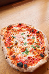 Pizza Margarita. Baked tasty margherita pizza in Traditional wood oven in Neapolitan restaurant, Italy.