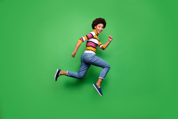 Fototapeta na wymiar Full size profile side photo of positive cheerful afro american girl jump run after fall black friday bargain wear denim jeans outfit isolated over green color background