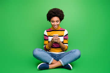 Full length photo of positive afro american girl blogger sit legs crossed folded use cellphone post...
