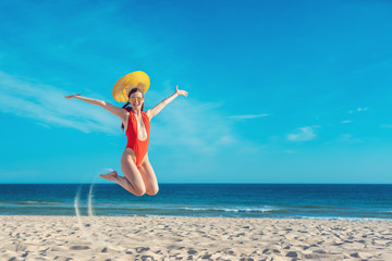 Beautiful woman enjoying her beach vacation jumping high
