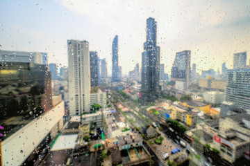 Obraz premium Bangkopk skyline view through a window, with rain drops, with the new and tallest building of Thailand, the Mahanakhon.