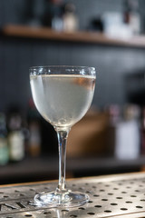 Transparent cocktail served on the wooden bar desk decorated with dried tropical flower