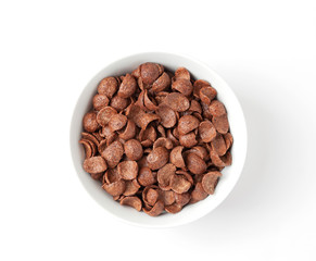 Chocolate cereal flakes in a white bowl, on white background. Crispy chocolate crunch corn flakes.  Top view.