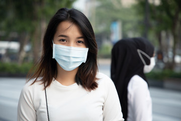 woman wearing mask in city with dirty polluted poison smog; concept of global warming, emission standard, dirty air, air pollution, environmental pollution, urban life problem, breathing difficult