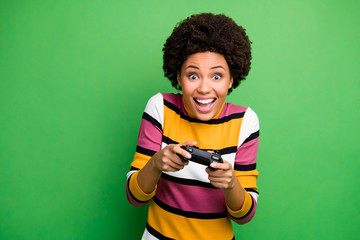 Photo of funny dark skin lady good mood playing video games addicted gamer excited hold joystick hands wear casual striped sweater isolated green color background