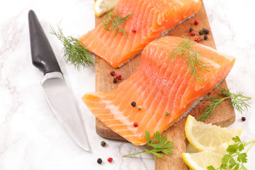raw salmon fillet on board with lemon and herbs
