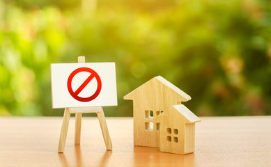 Wooden houses and an easel with a red prohibition sign NO. Inaccessibility and lack of housing,...