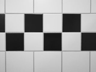 Small square tiles alternately arranged in black and white as a pattern - above and below are larger, square white tiles - separated by joints.